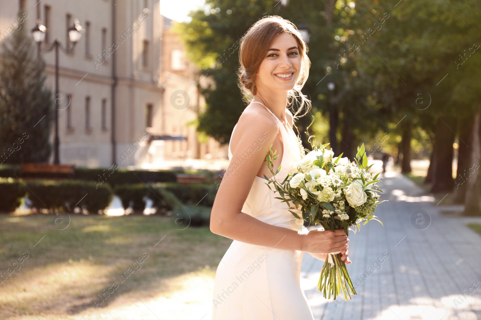 Photo of Gorgeous bride in beautiful wedding dress with bouquet outdoors