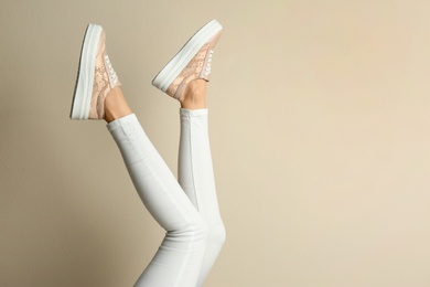 Woman wearing shoes on beige background, closeup. Space for text