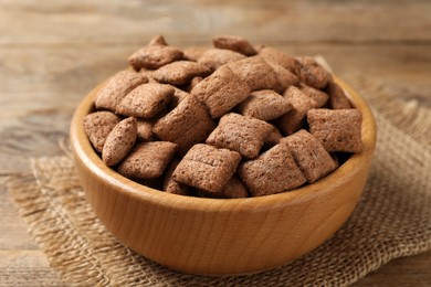 Sweet crispy corn pads in bowl on wooden table, closeup