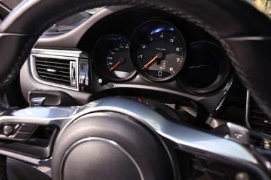 Steering wheel, speedometer and tachometer inside of modern car, closeup