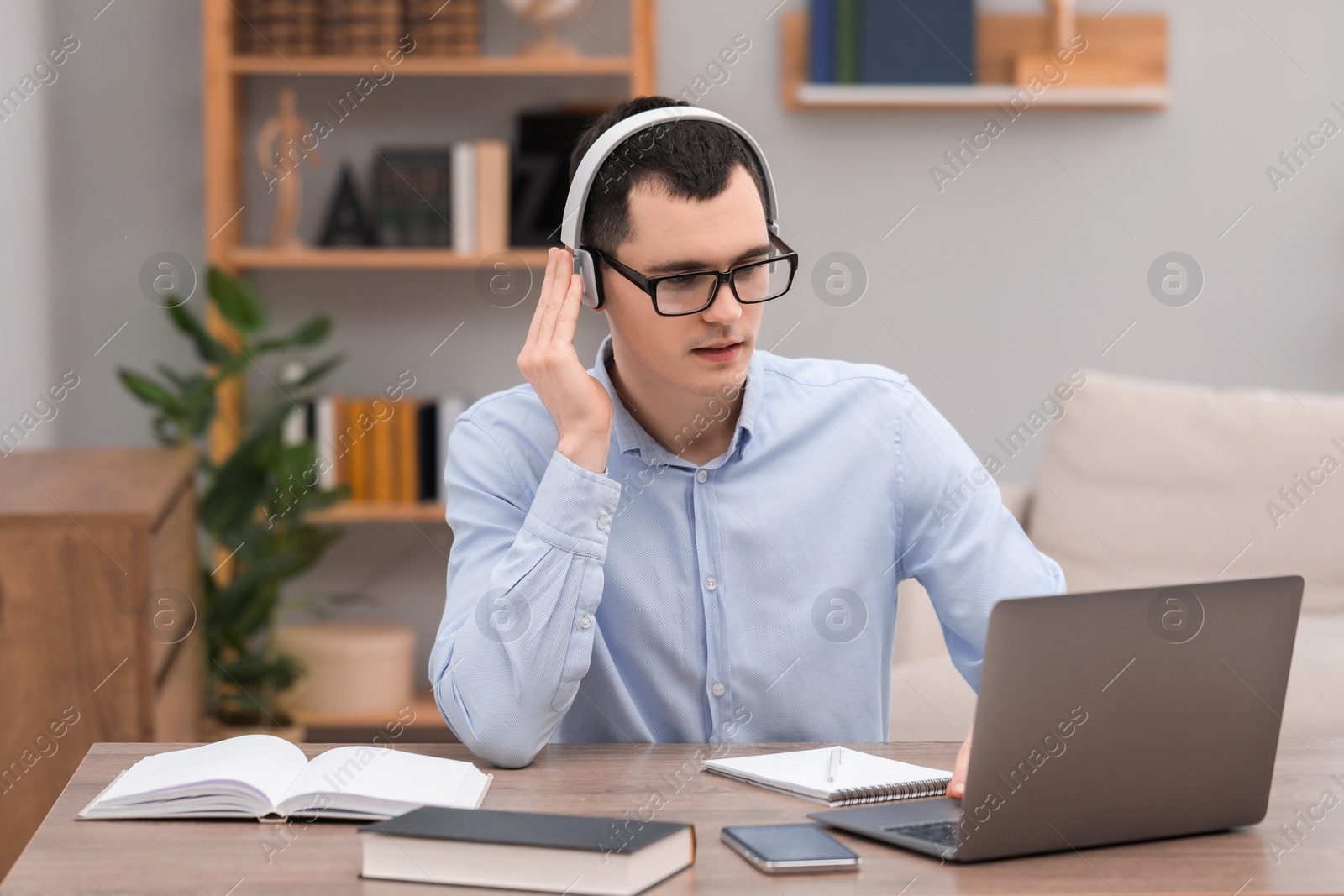 Photo of E-learning. Young man using laptop during online lesson at table indoors.