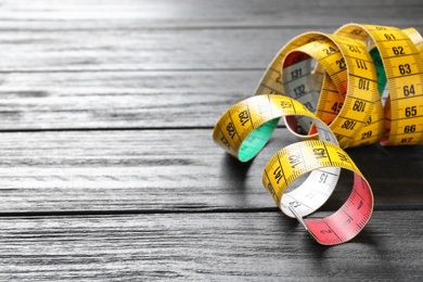 Photo of Measuring tape on wooden background. Tailoring equipment