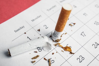 Photo of Calendar sheet with broken cigarette, closeup. Quitting smoking concept
