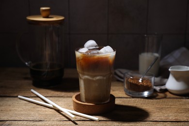 Photo of Refreshing iced coffee in glass and straws on wooden table