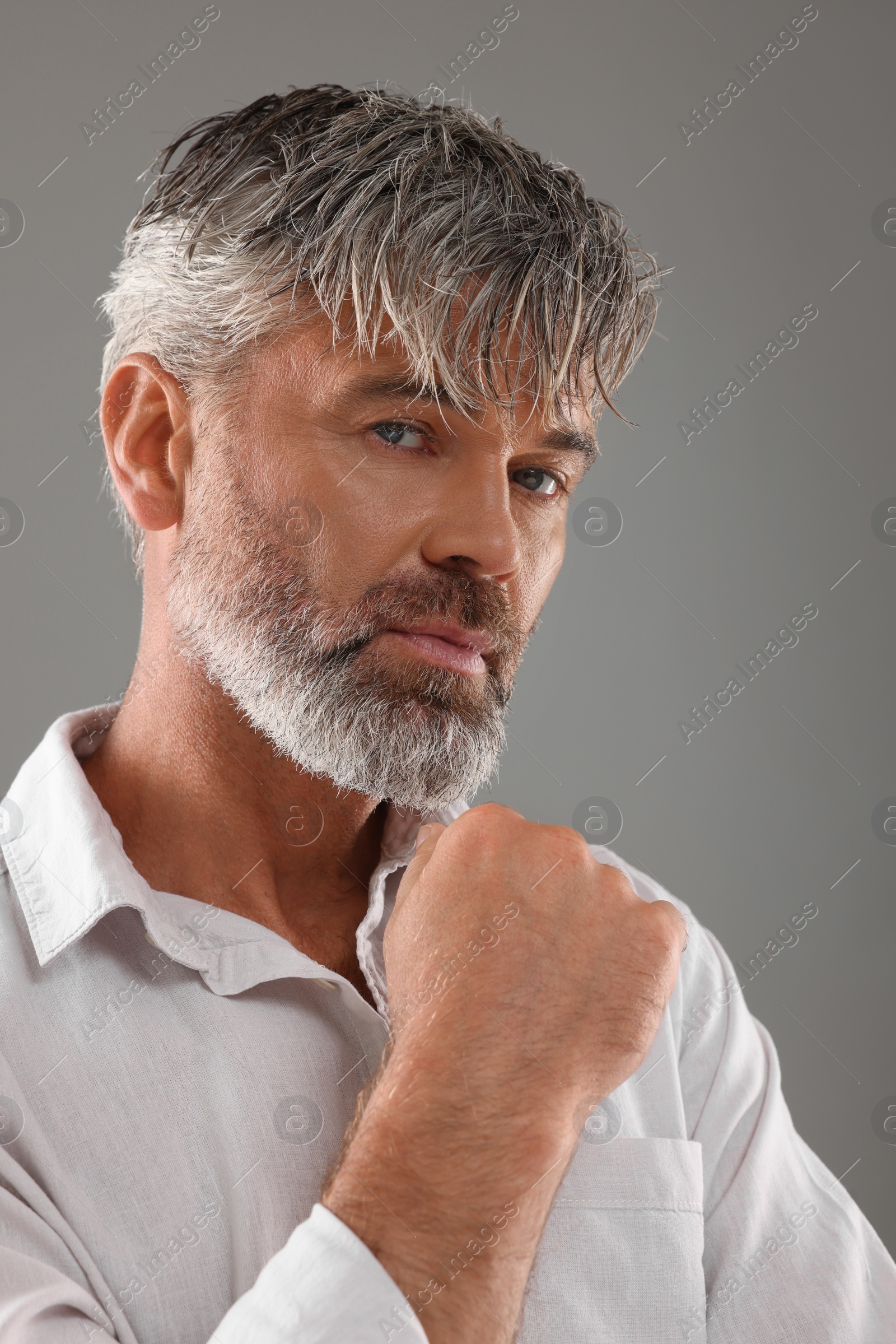 Photo of Portrait of confident man with beautiful hairstyle on light grey background
