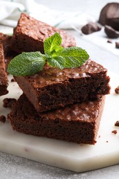 Delicious chocolate brownies with fresh mint on grey table, closeup
