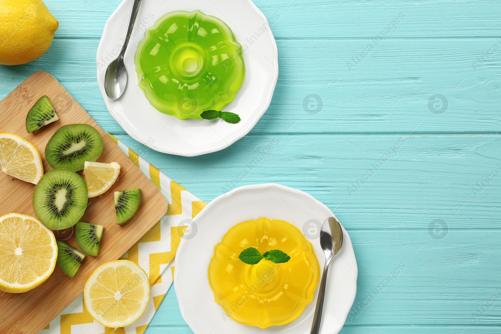 Photo of Flat lay composition with plates of jelly and tropical fruits on blue wooden table. Space for text