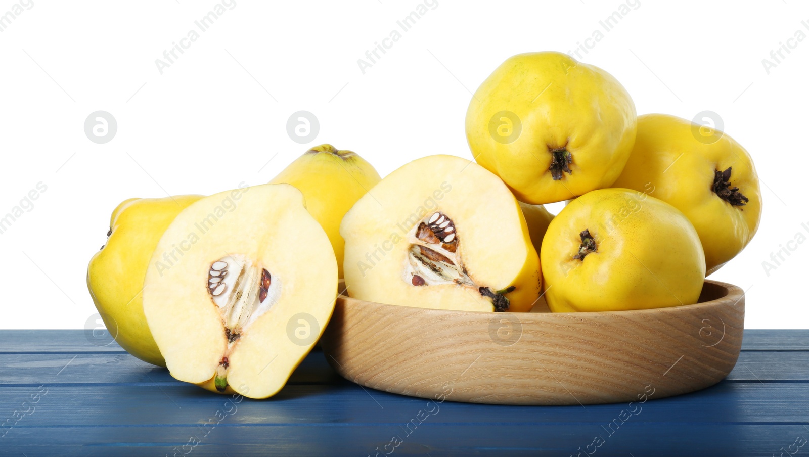 Photo of Ripe whole and cut quinces on blue wooden table against white background