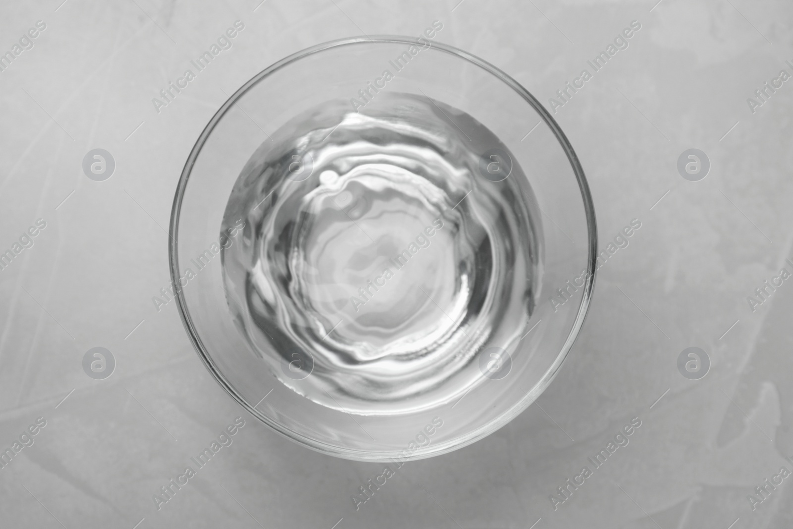 Photo of Glass bowl with water on grey table, top view