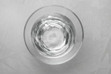 Glass bowl with water on grey table, top view