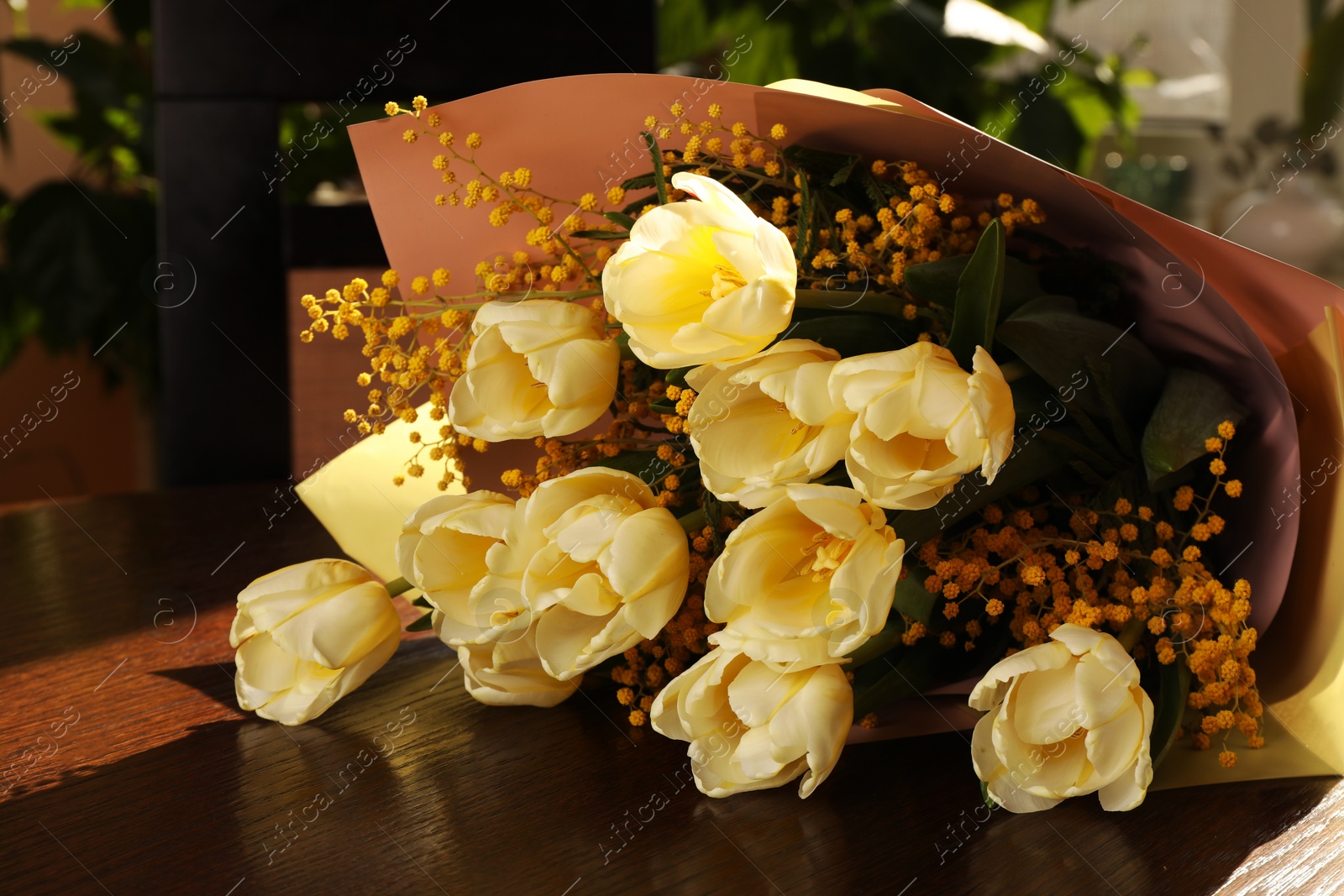 Photo of Bouquet with beautiful tulips and mimosa flowers on wooden table indoors