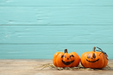 Photo of Pumpkins with scary faces on light blue wooden background, space for text. Halloween decor