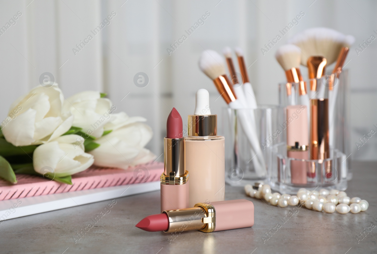 Photo of Different decorative cosmetics, brushes and white tulips on grey table