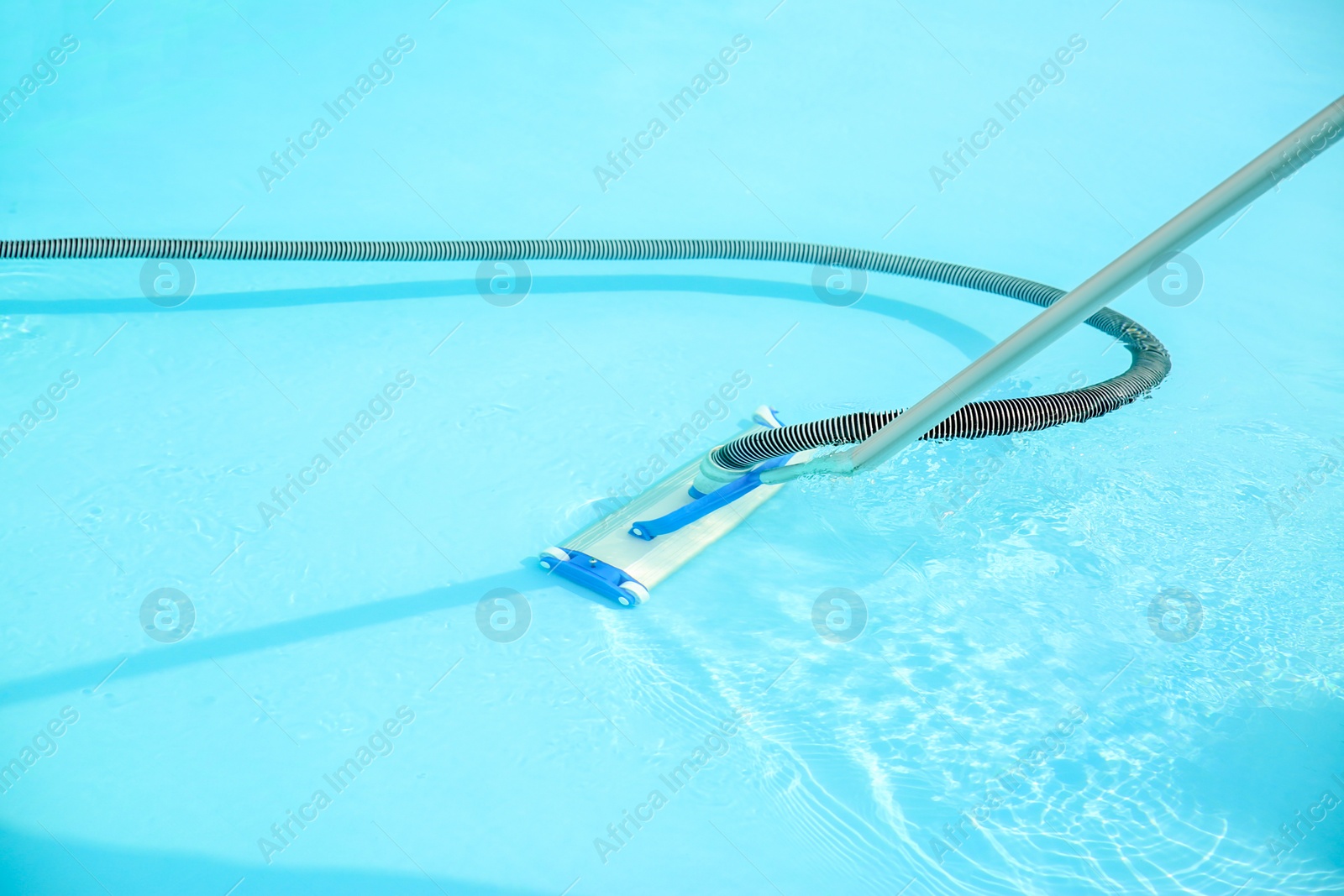 Photo of Cleaning outdoor pool with underwater vacuum, closeup