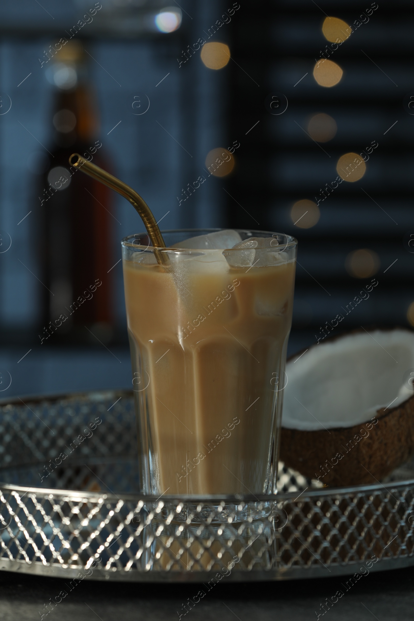 Photo of Glass of iced coffee and coconut on grey table against blurred lights