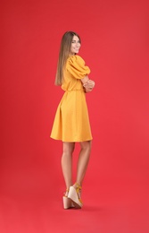 Young woman wearing stylish yellow dress on red background