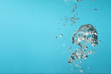 Air bubbles in water on light blue background. Space for text