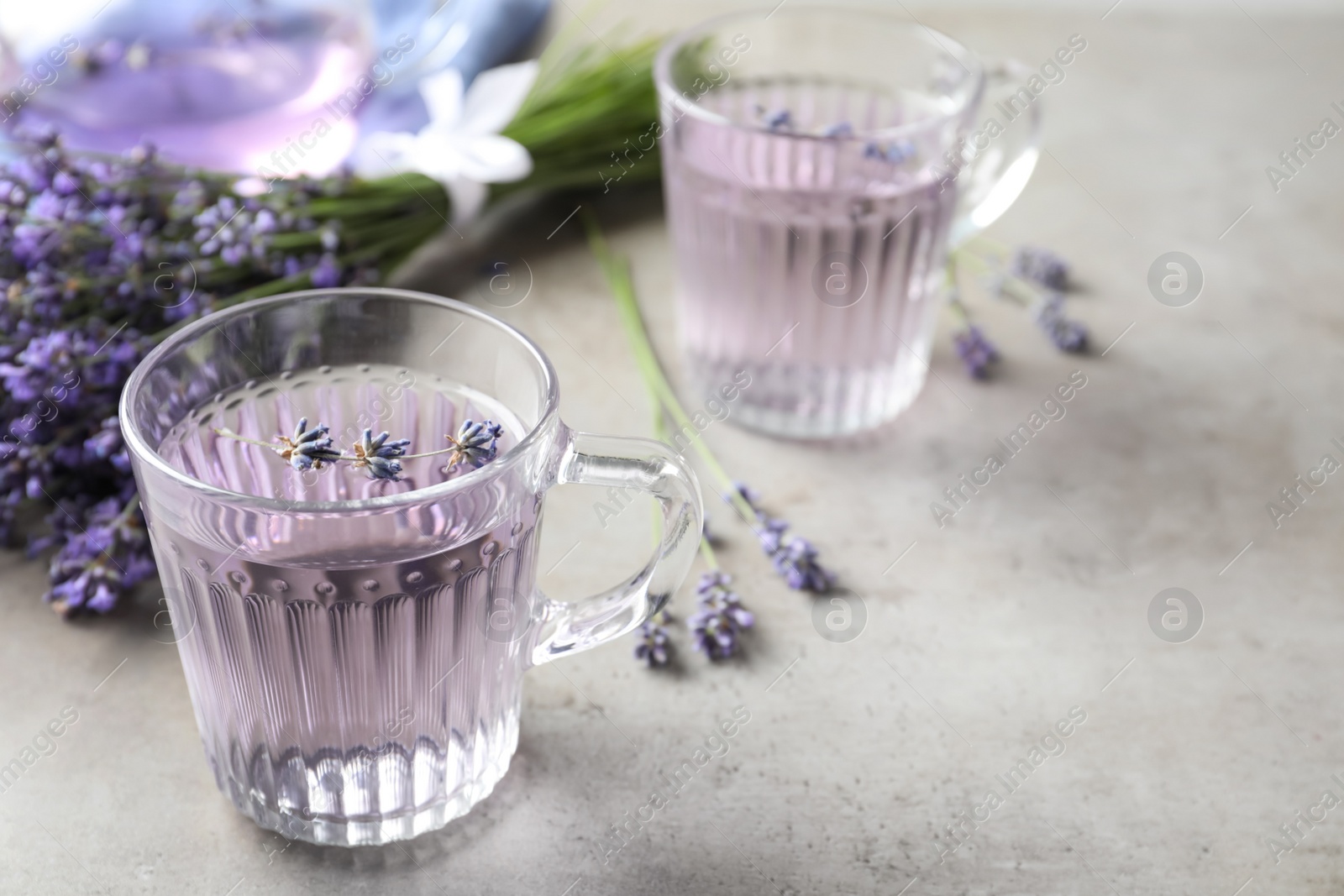 Photo of Fresh delicious drink with lavender in glass cup on grey table. Space for text