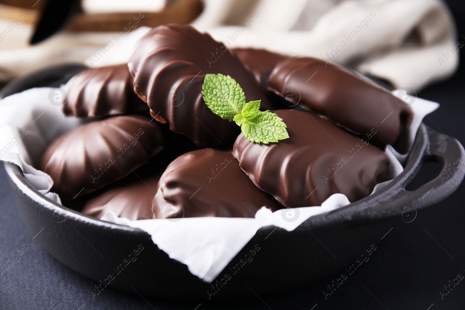 Photo of Delicious chocolate covered marshmallows with mint on black table, closeup