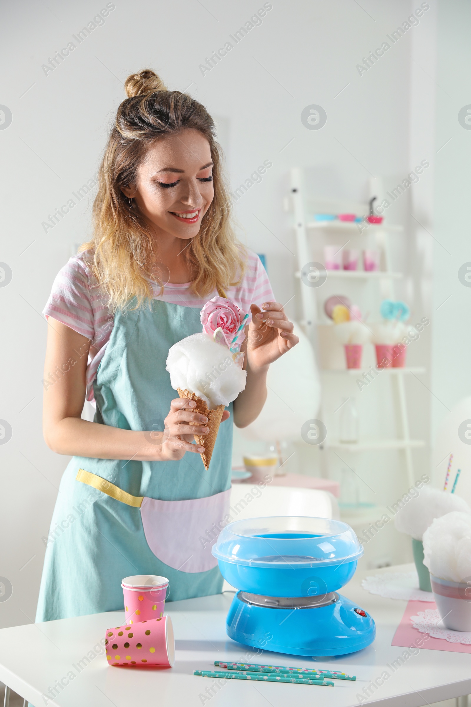 Photo of Young woman with cotton candy dessert at table