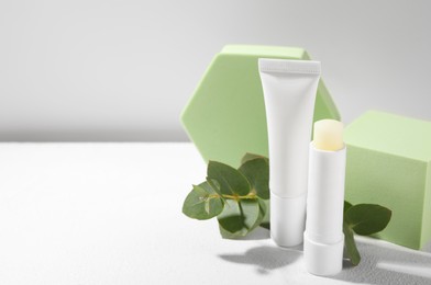 Photo of Stylish presentation of different lip balms on white table, space for text