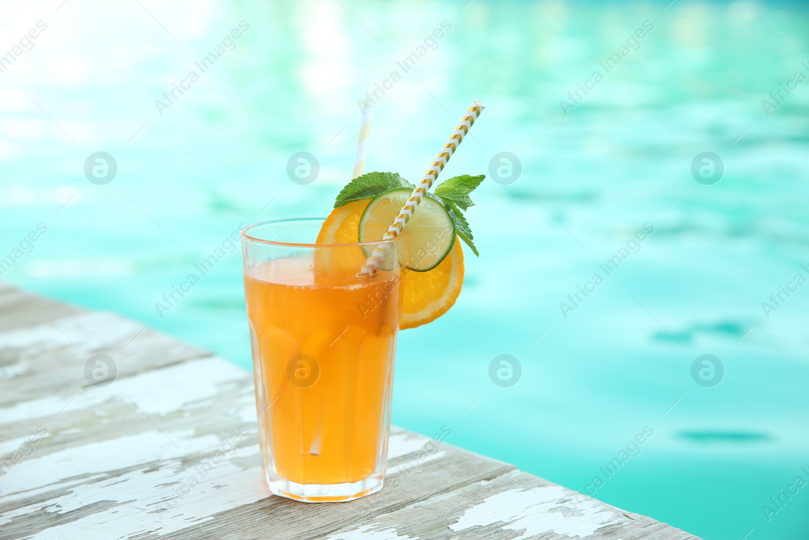 Photo of Refreshing cocktail near outdoor swimming pool on sunny day. Space for text