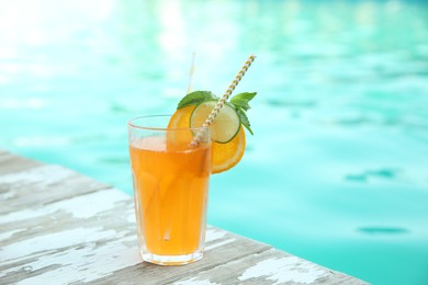 Refreshing cocktail near outdoor swimming pool on sunny day. Space for text