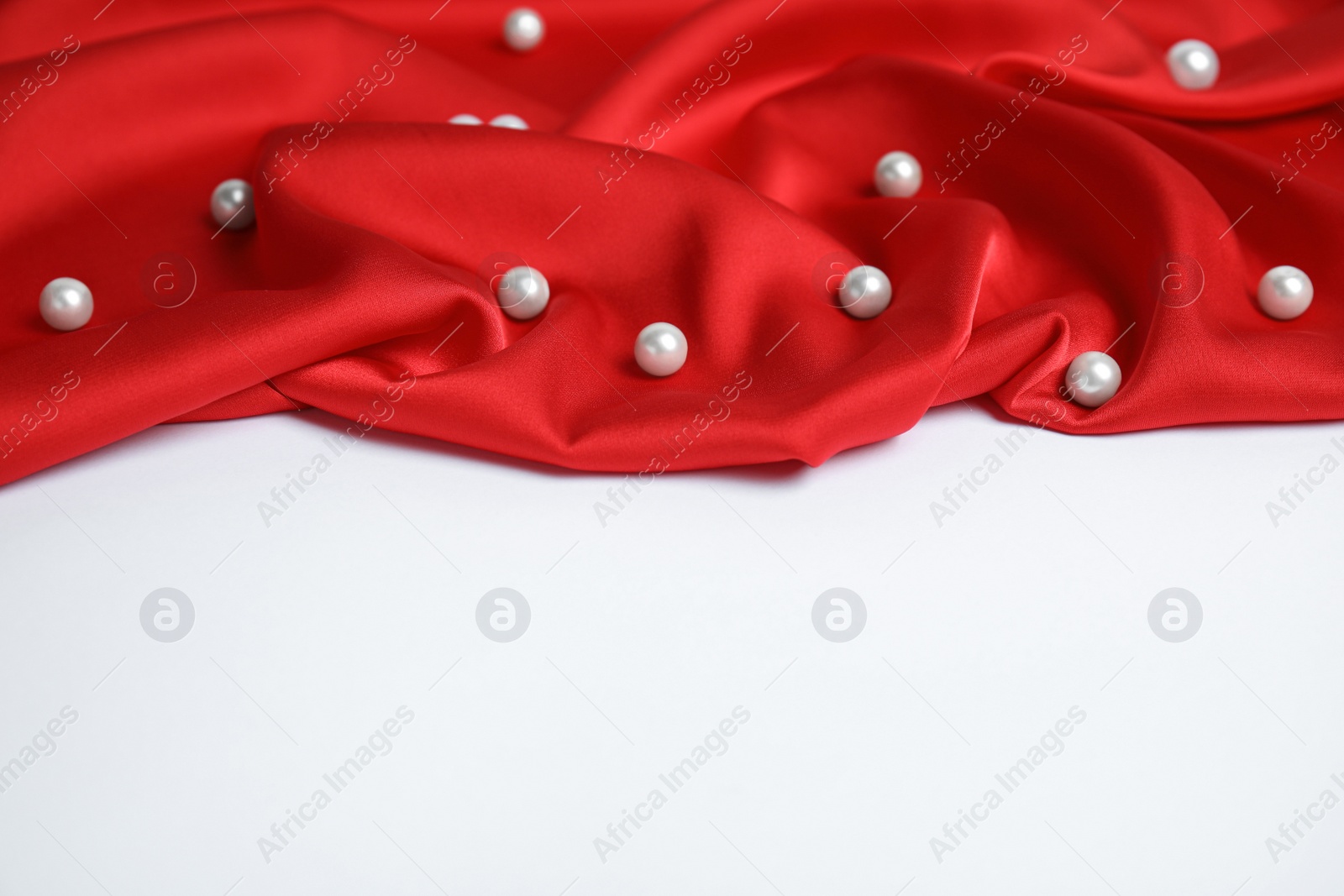 Photo of Texture of delicate red silk with pearls on white background