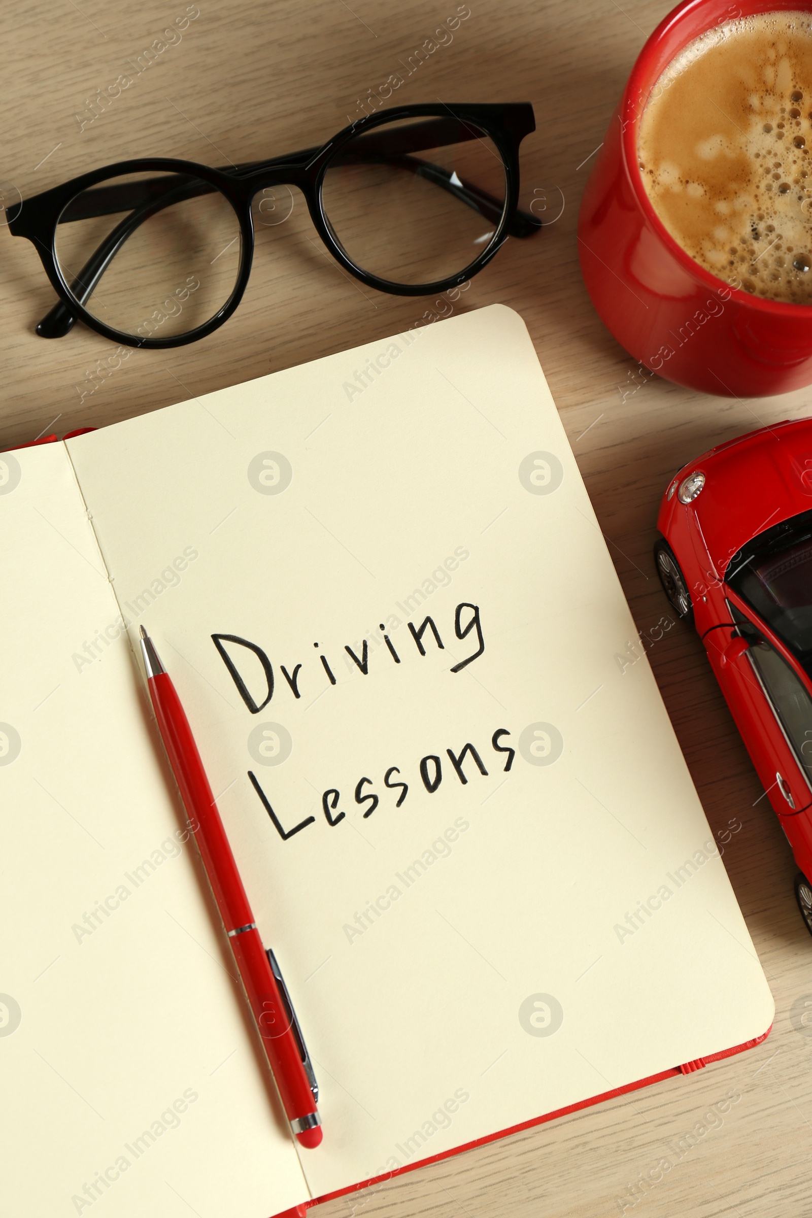 Photo of Flat lay composition with workbook for driving lessons and cup of coffee on white wooden background. Passing license exam