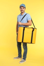 Photo of Young courier with thermo bag on color background. Food delivery service