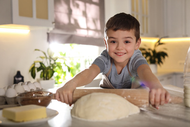 Cute little boy rolling dough at table in kitchen. Cooking pastry