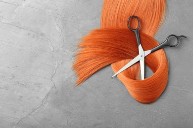 Flat lay composition with red hair, scissors and space for text on grey background. Hairdresser service