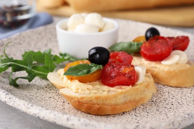 Photo of Plate of delicious tomato bruschettas on table, closeup