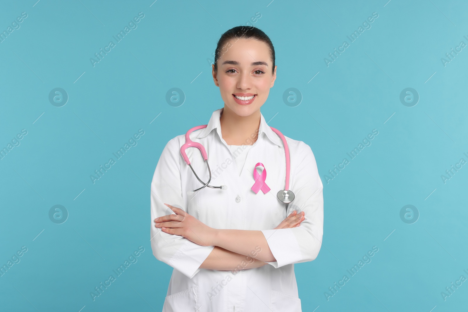 Photo of Mammologist with pink ribbon on light blue background. Breast cancer awareness