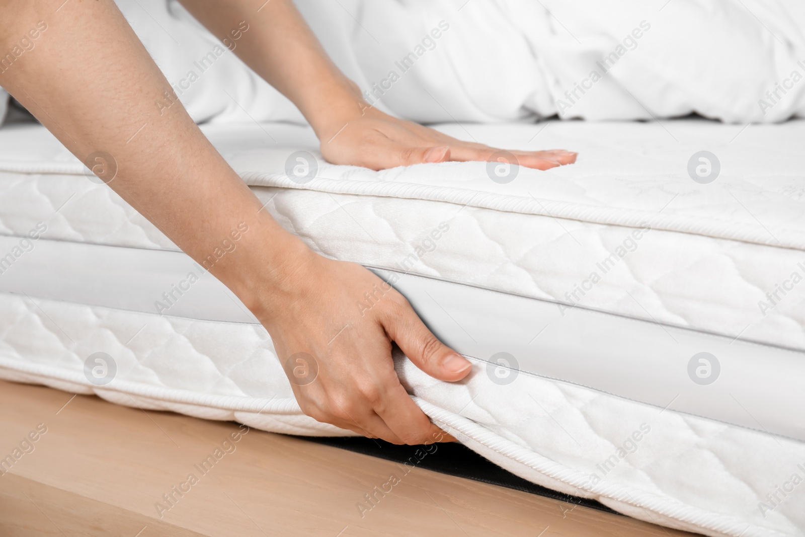 Photo of Woman touching soft white mattress on bed, closeup