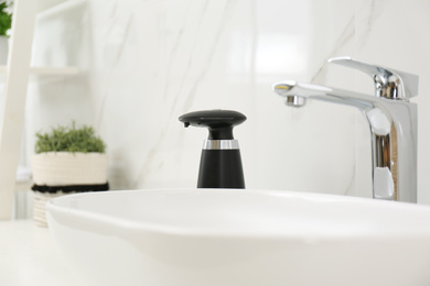 Photo of Modern automatic soap dispenser near sink in bathroom, closeup