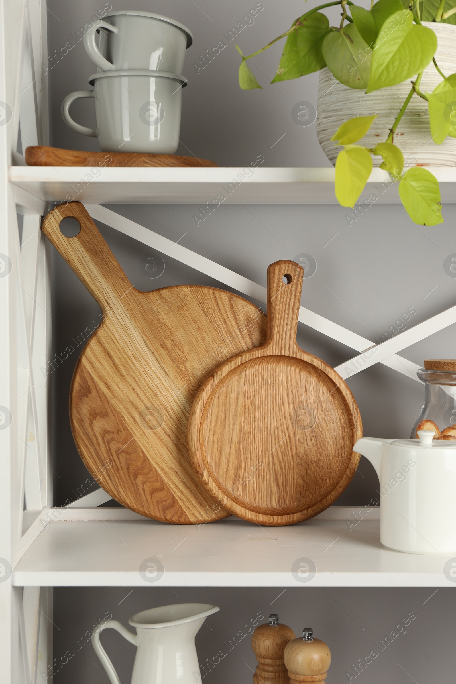 Photo of Wooden cutting boards and kitchen utensils on shelving unit