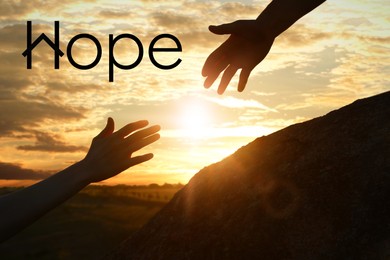 Image of Concept of hope. Man helping woman to climb on hill at sunset, closeup
