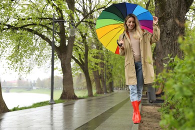 Photo of Young woman with umbrella walking in park on spring day