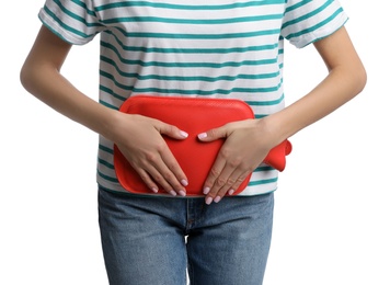 Woman using hot water bottle to relieve menstrual pain on white background, closeup
