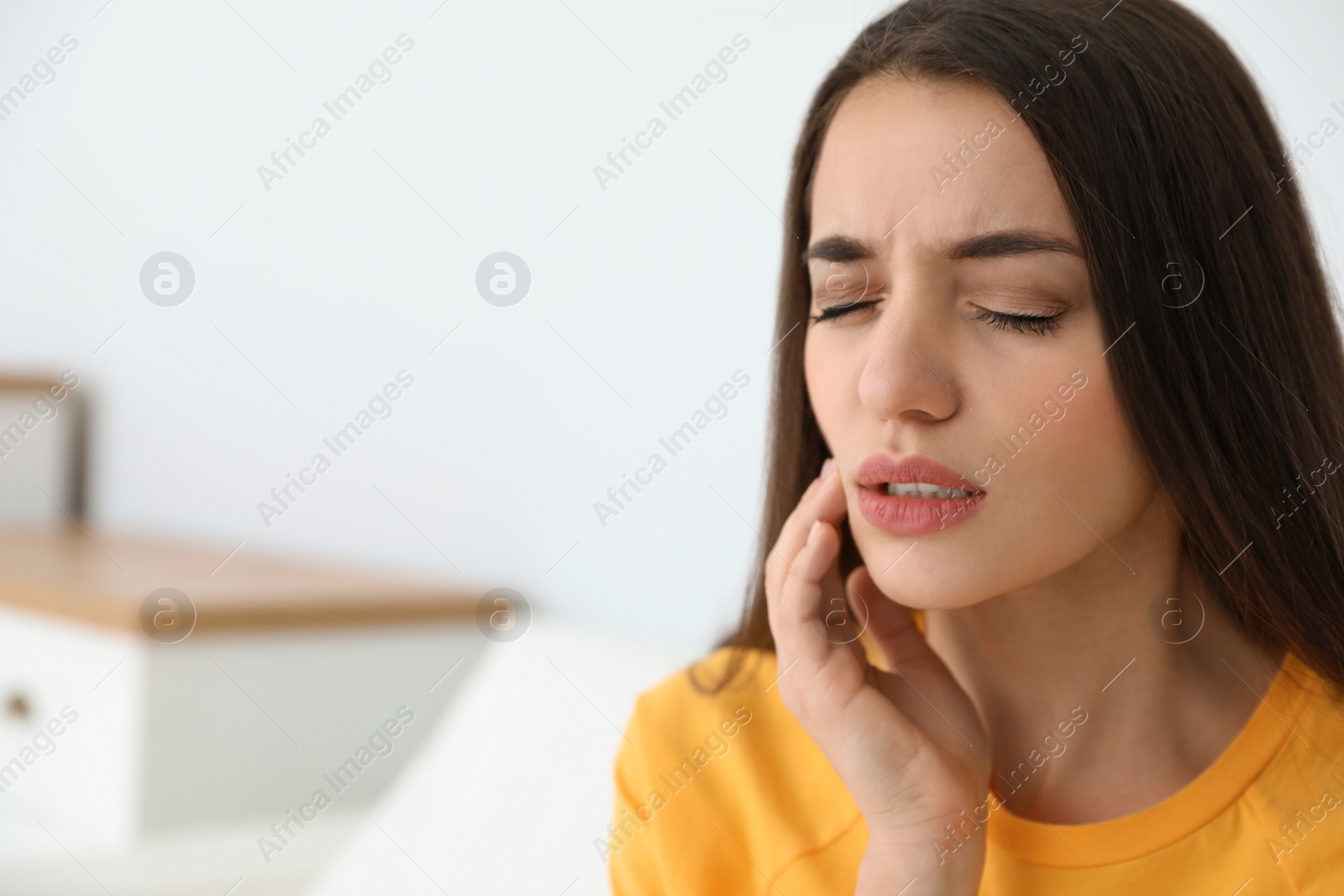 Photo of Young woman suffering from strong tooth pain at home, space for text