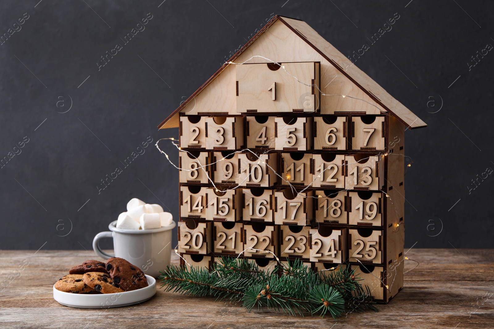 Photo of House shaped Christmas advent calendar, cookies and hot cocoa drink on wooden table