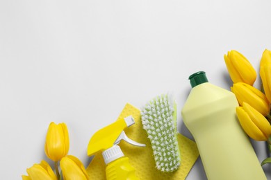 Spring cleaning. Detergents, flowers, brush and rag on white background, flat lay. Space for text