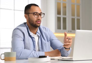 Young man having online video chat at desk in kitchen. Home office