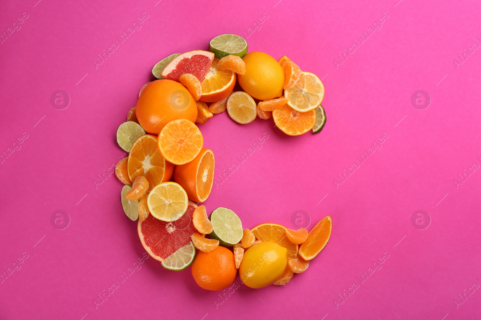 Photo of Letter C made with citrus fruits on pink background as vitamin representation, flat lay