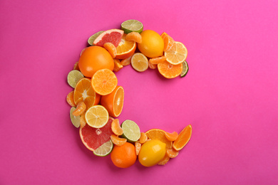 Letter C made with citrus fruits on pink background as vitamin representation, flat lay