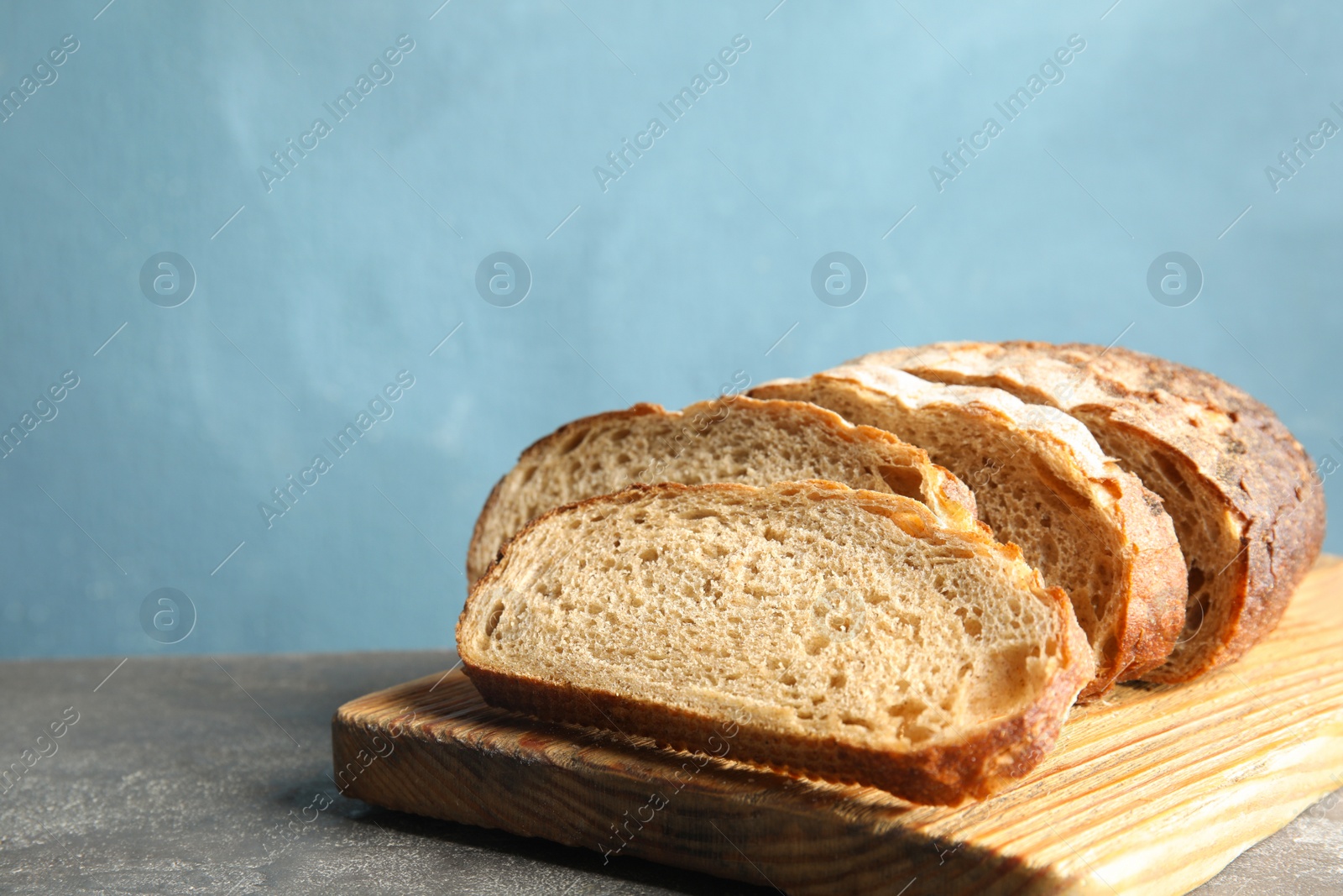 Photo of Board with bread on grey table, space for text