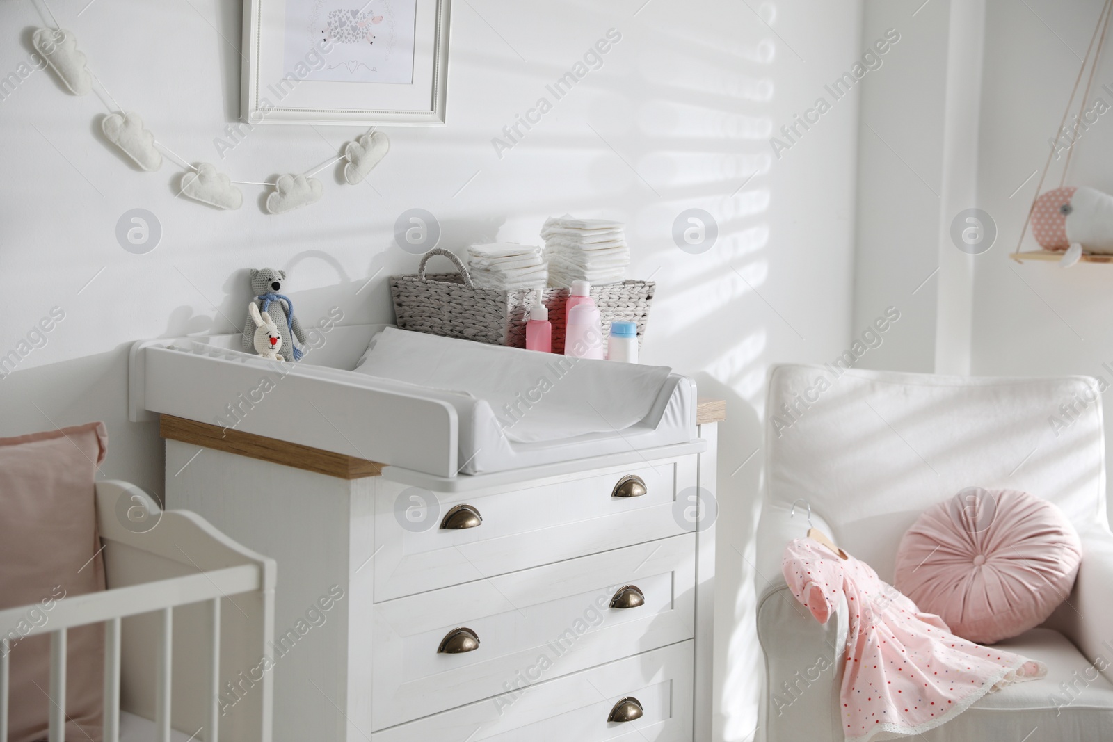 Photo of Chest of drawers with changing tray and pad in baby room. Interior design