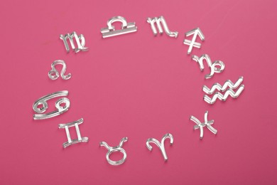 Photo of Zodiac signs on pink background, above view. Space for text