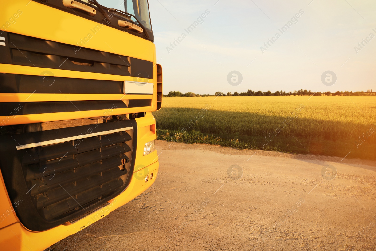 Photo of Modern yellow truck on country road, closeup. Space for text